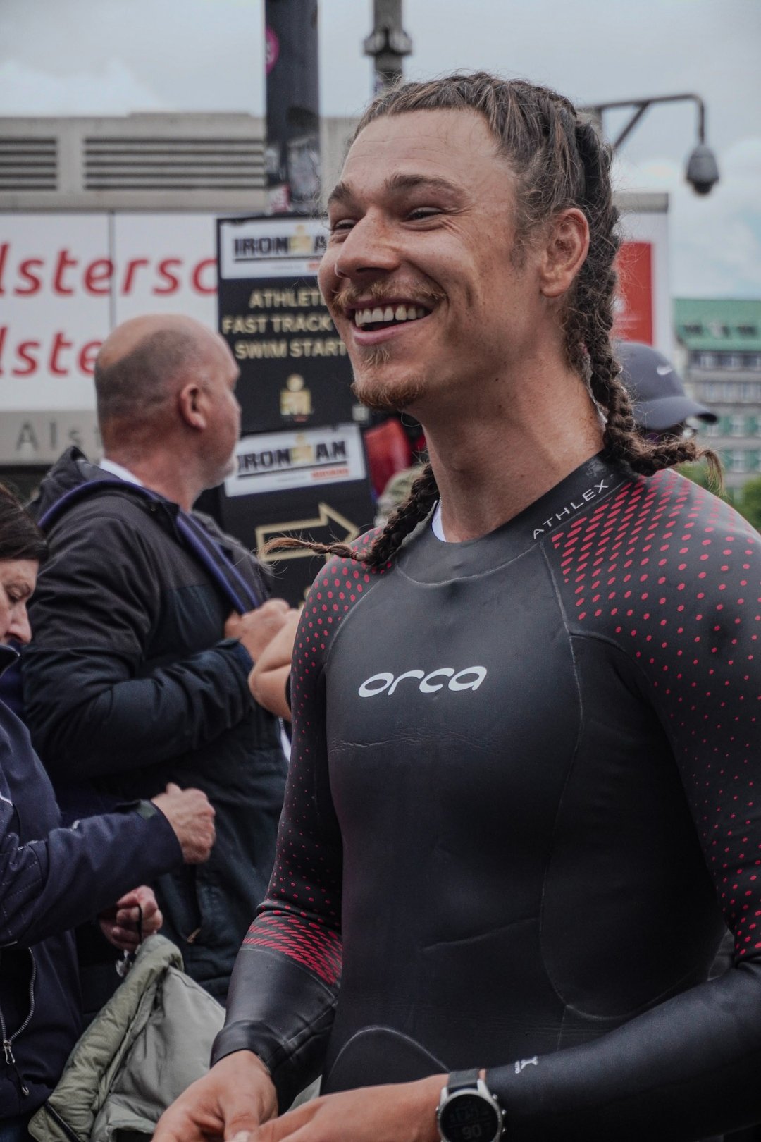 Ritschi im Orca Neopren vor dem Schwimmstart, großes Lächeln, Ironman Swim Start Schild